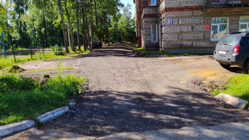 Грунтовая дорога и деревья около многоквартирного дома