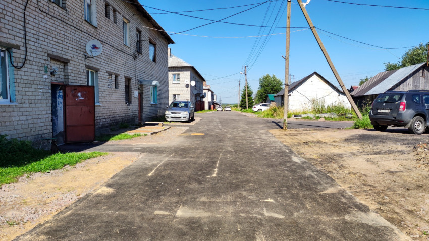 Свежеасфальтированная улица с жилыми зданиями и припаркованными автомобилями