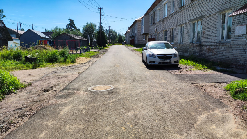 Новая асфальтированная улица рядом с жилыми домами и припаркованной машиной