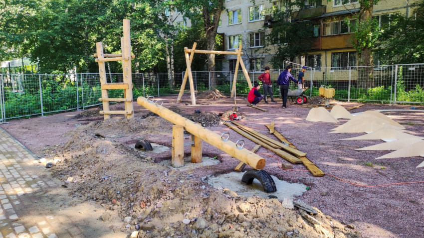 Детская площадка в процессе строительства с деревянными качелями и горками