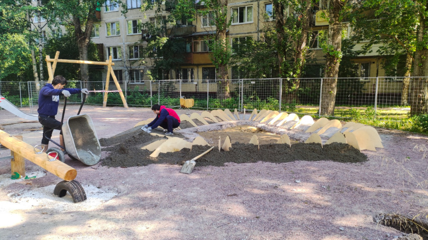 Двое строителей на детской площадке с бетонным раствором и лопатами