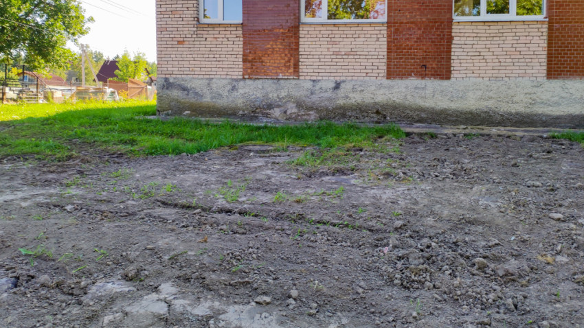 Неасфальтированная территория рядом с кирпичным зданием