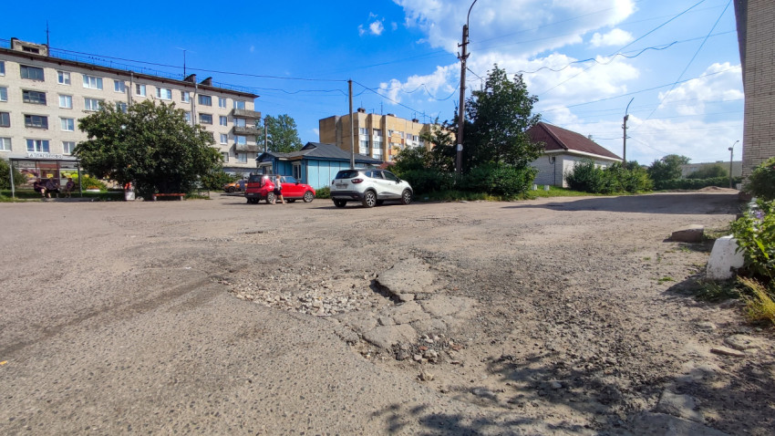 Поврежденная асфальтовая дорога с ямами в жилом районе