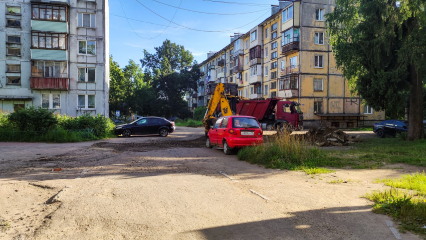 Строительная площадка во дворе с экскаватором и красным автомобилем