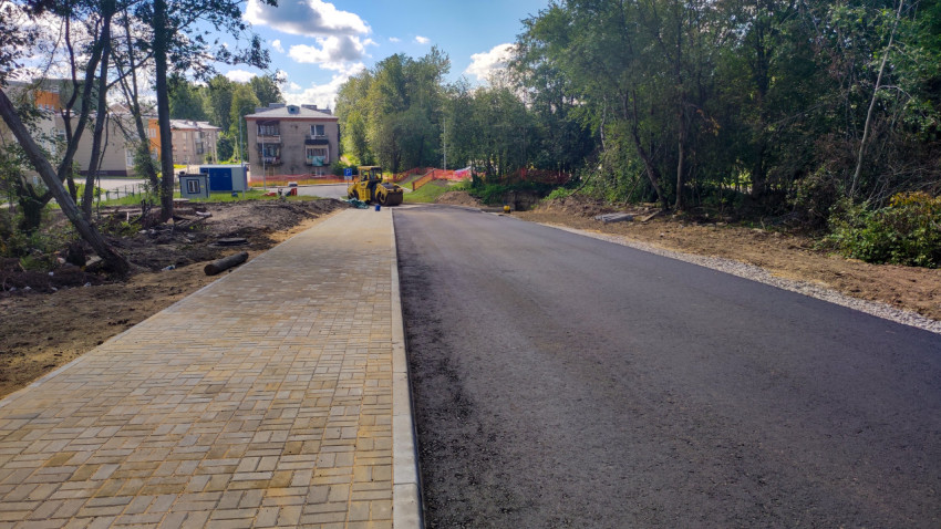 Новая асфальтированная дорога с тротуаром и зелеными насаждениями
