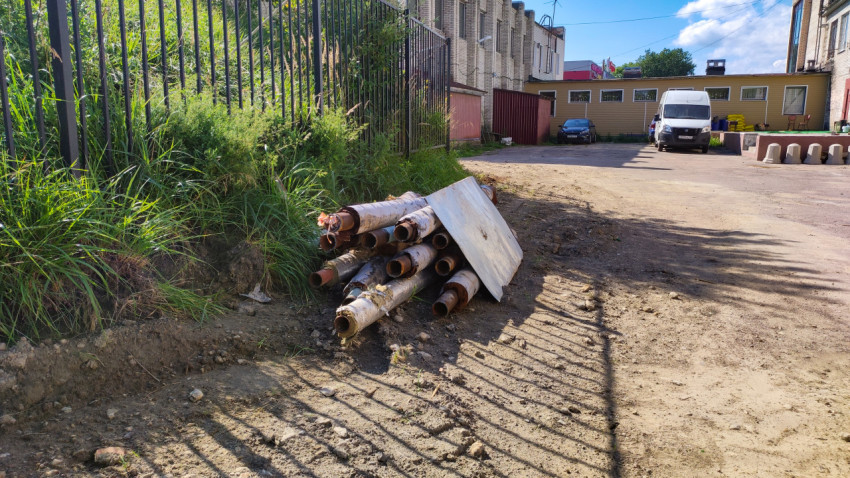Старые металлические трубы на земле возле зданий