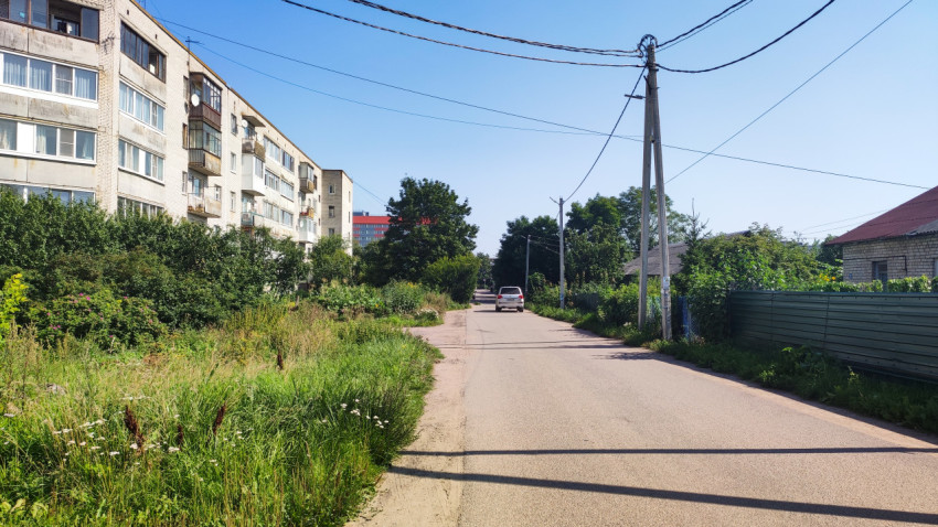 Улица с жилыми домами, деревьями и дорогой в ясный день