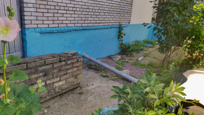 Отмостка жилого дома с кирпичной стеной и синей полосой