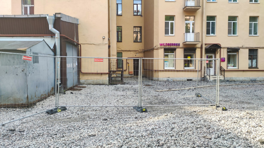 Строительная площадка с ограждением и зданиями на заднем плане
