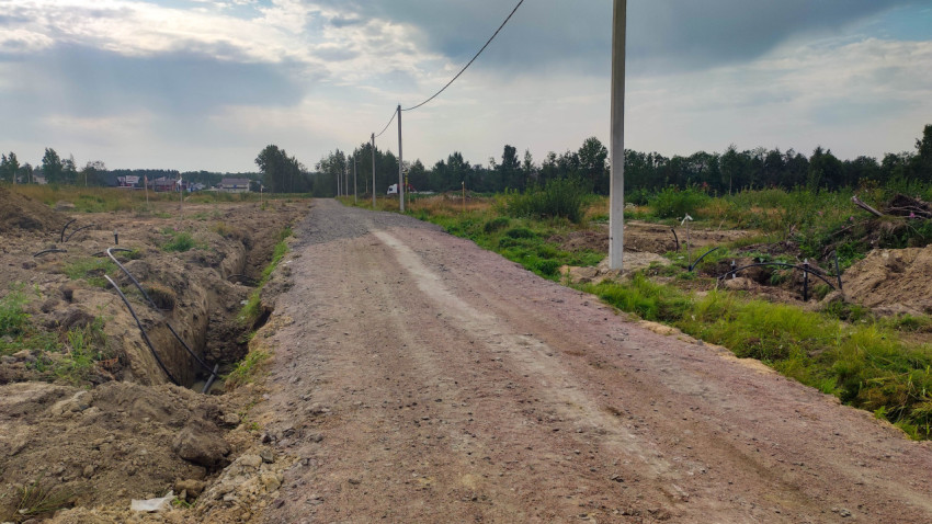 Грунтовая дорога вдоль вырытой канавы с трубами