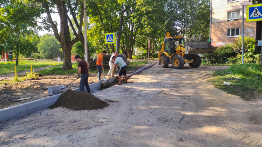 Строительная площадка с экскаватором-погрузчиком JCB 3CX и людьми, работающими на дороге