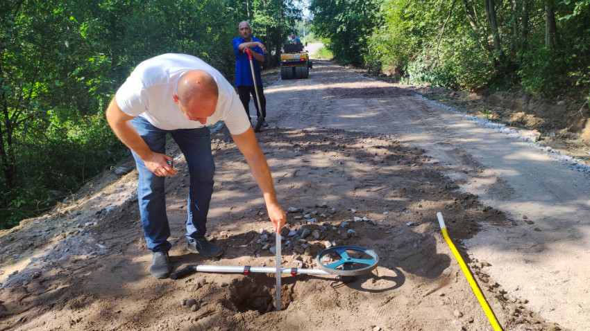 Мужчина измеряет глубину основания строящейся дороги