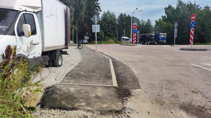 Участок дороги с отремонтированным тротуаром и несколькими дорожными знаками