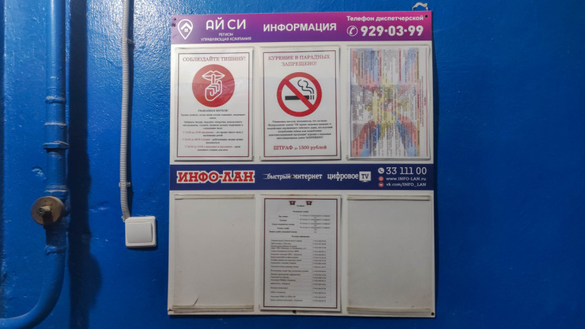 Информационный стенд в подъезде с табличками о соблюдении тишины и запрете курения, а также о штрафе за курение в парадных