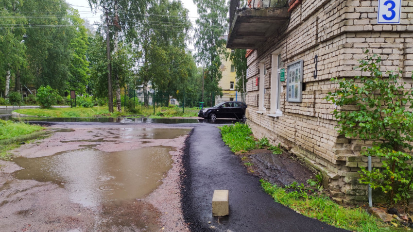 Асфальтированная тропинка возле кирпичного дома в дождливый день