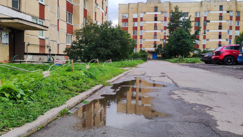 Жилой двор с лужами, зеленью и советскими панельными домами