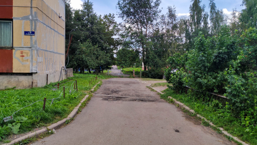 Выезд со двора в жилом районе с зелеными насаждениями и панельными домами