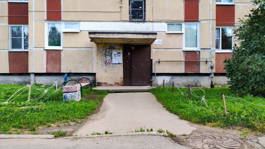 Подъезд многоквартирного дома с асфальтированной дорожкой и уличной скамейкой