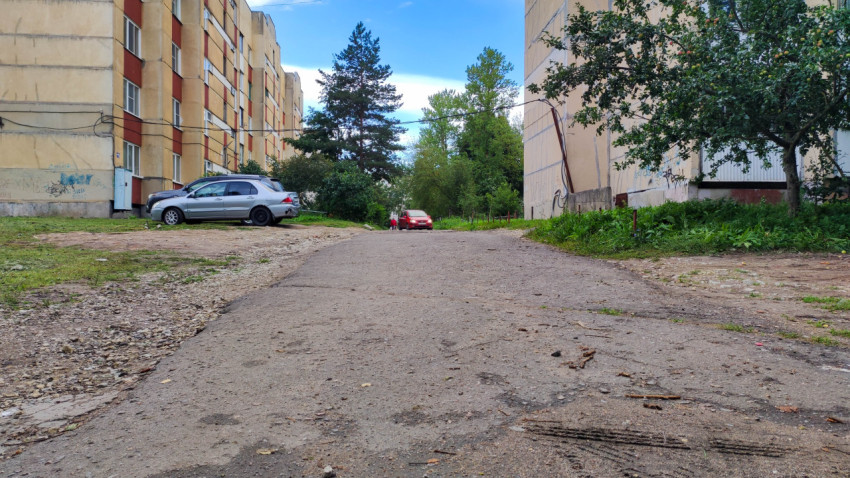 Двор жилого дома с дорогой и проезжающим автомобилем