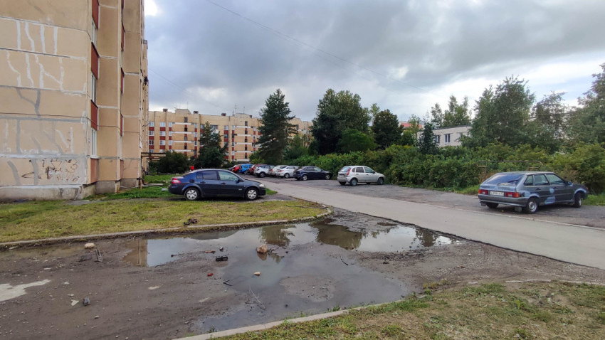 Парковка во дворе многоквартирного дома с лужами на асфальте