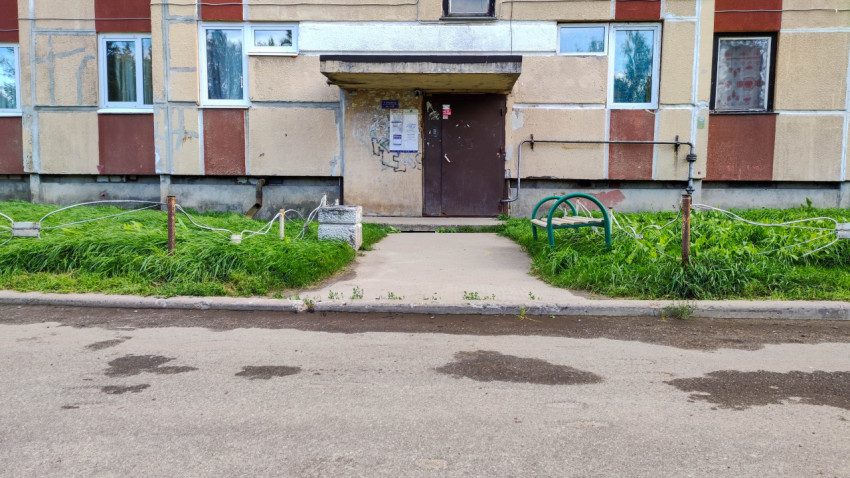 Подъезд многоквартирного дома с травяным участком и уличной мебелью