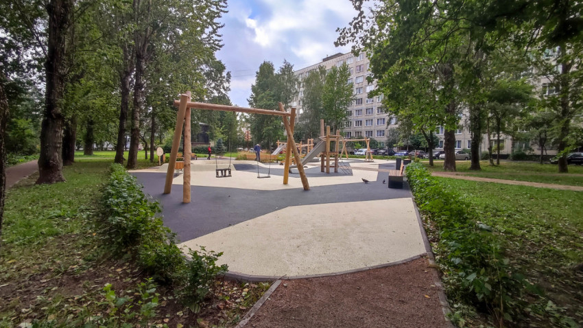 Современная детская площадка с качелями и горкой в парковой зоне