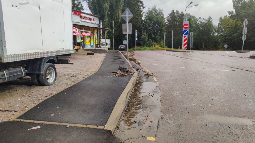 Разрушенный бордюр и повреждённый тротуар возле магазина на улице