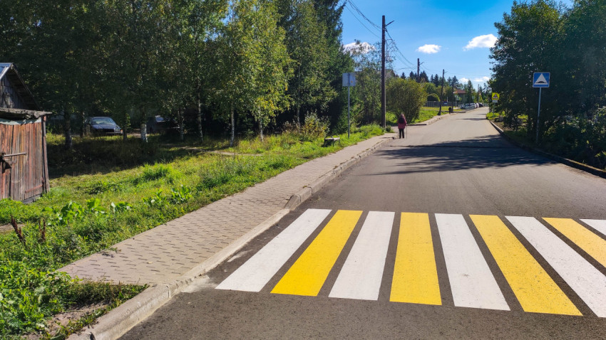Пешеходный переход на улице поселка с тротуаром и зелеными насаждениями