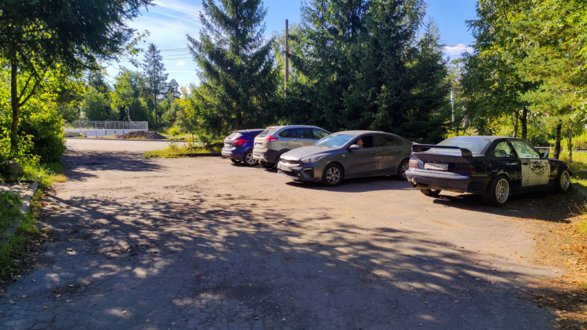 Старая парковка с потрескавшимся асфальтом и припаркованными автомобилями