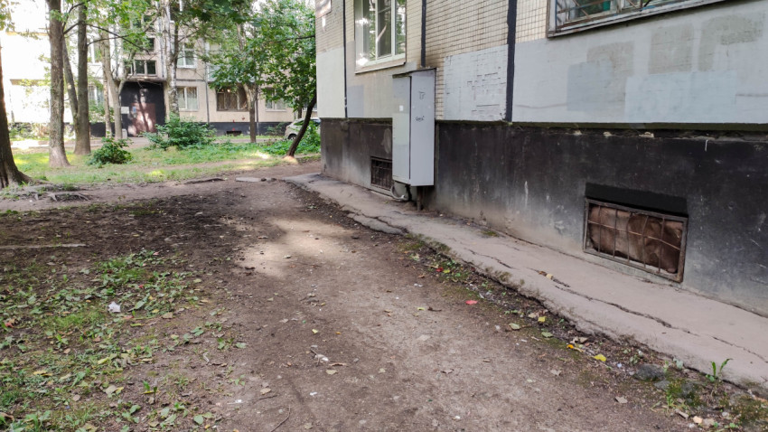 Придомовая территория с неухоженной землёй и коммуникационным шкафом