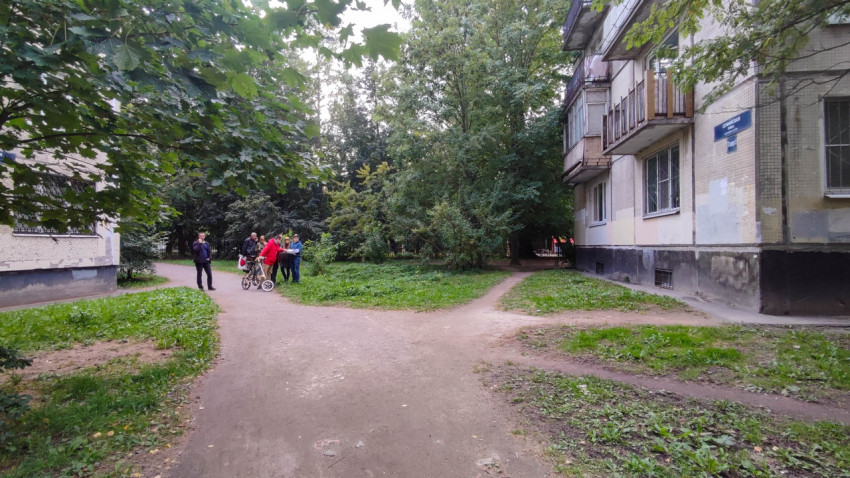 Группа людей обсуждает благоустройство придомовой территории возле жилого дома