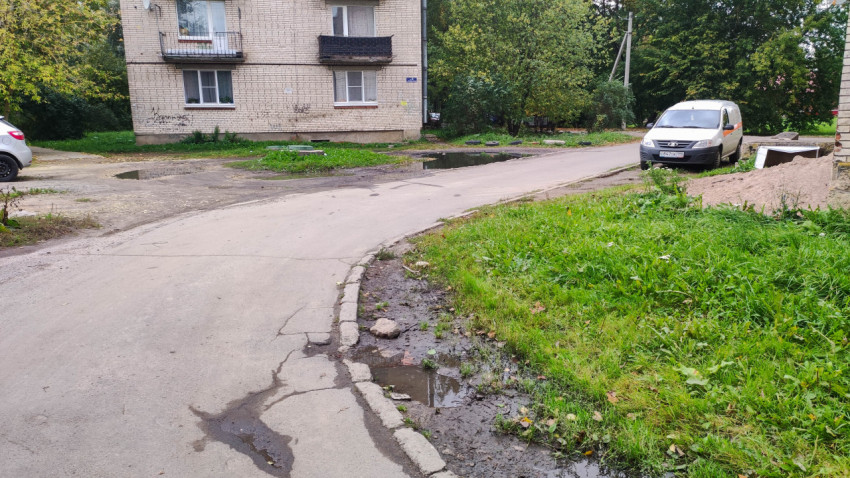 Асфальтированная дорога с лужами возле жилого дома