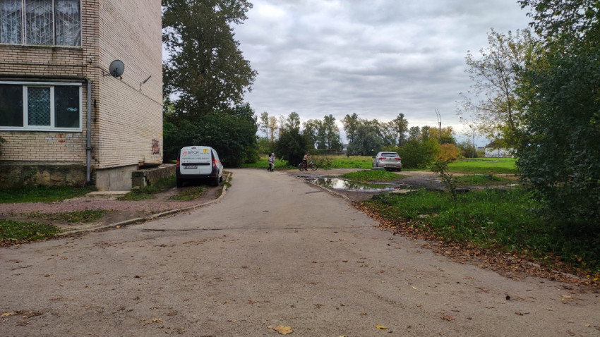Жилой двор с припаркованными машинами и лужей возле дороги