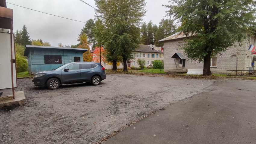 Двор с припаркованным внедорожником и кирпичным домом в поселковой зоне