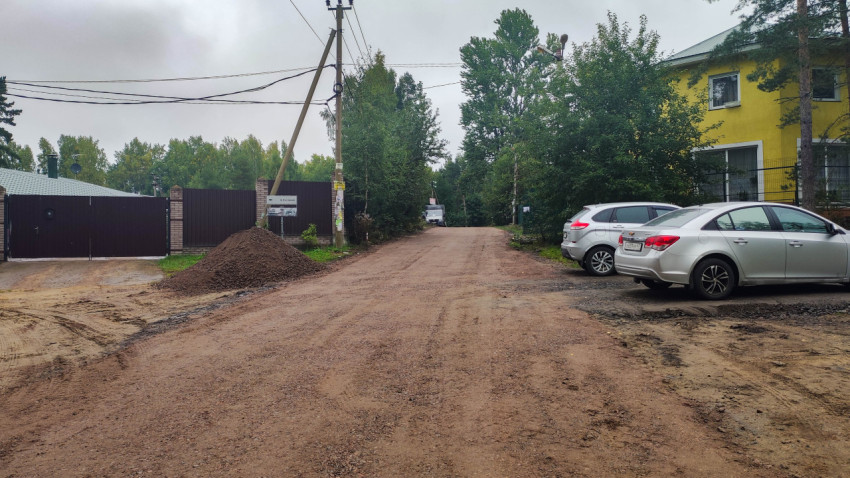 Грунтовая дорога с припаркованными автомобилями и прилегающими участками