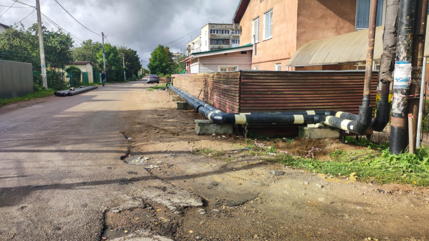 Наружный трубопровод и деревянный забор вдоль поселковой улицы