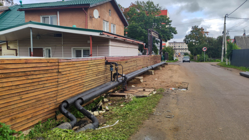 Дом с деревянным забором и наружным трубопроводом на улице поселка