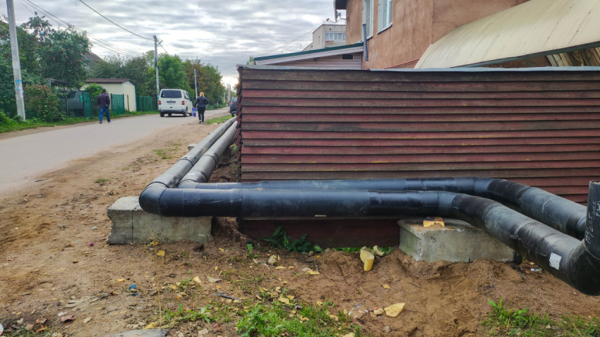 Трубопровод вдоль деревянного забора на городской улице