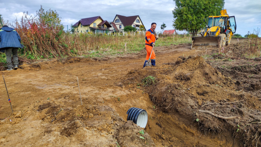 Рабочие и техника на стройке в загородном поселке