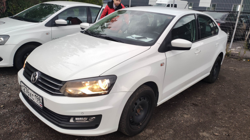Volkswagen Polo с включёнными фарами на парковке