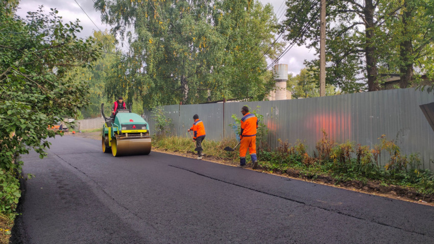 Каток Ammann на свежем асфальте и рабочие с лопатами