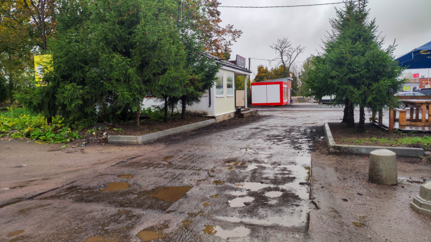 Разбитая асфальтированная дорога возле торговых павильонов
