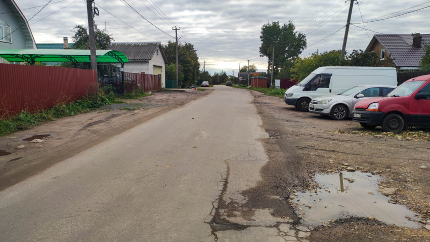 Парковка автомобилей вдоль поврежденной дороги в частном секторе
