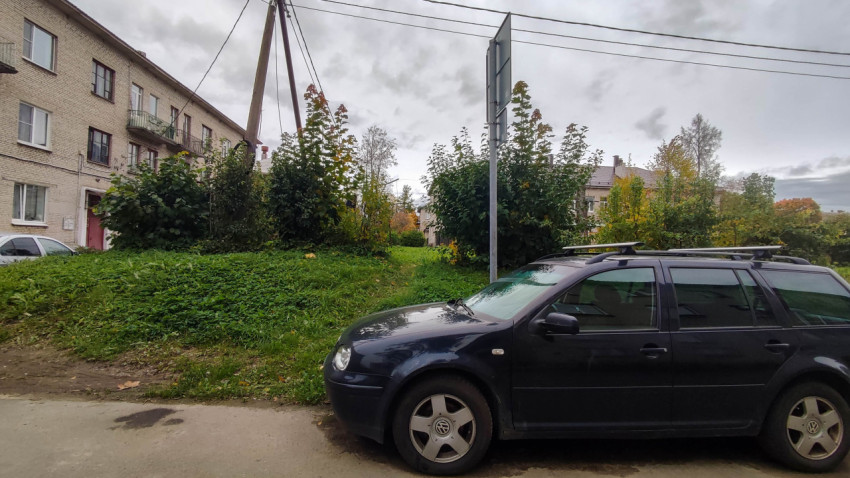 Жилой двор с припаркованными автомобилями, зеленью и кирпичными домами