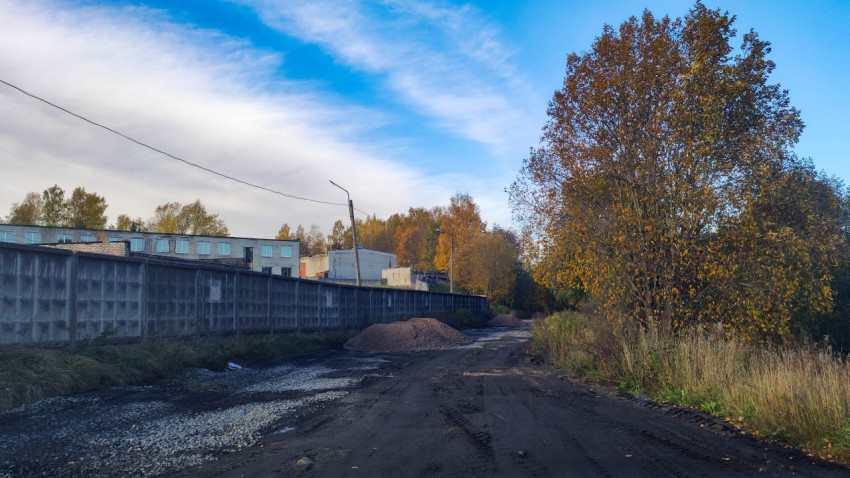 Грунтовая дорога вдоль бетонного забора осенью