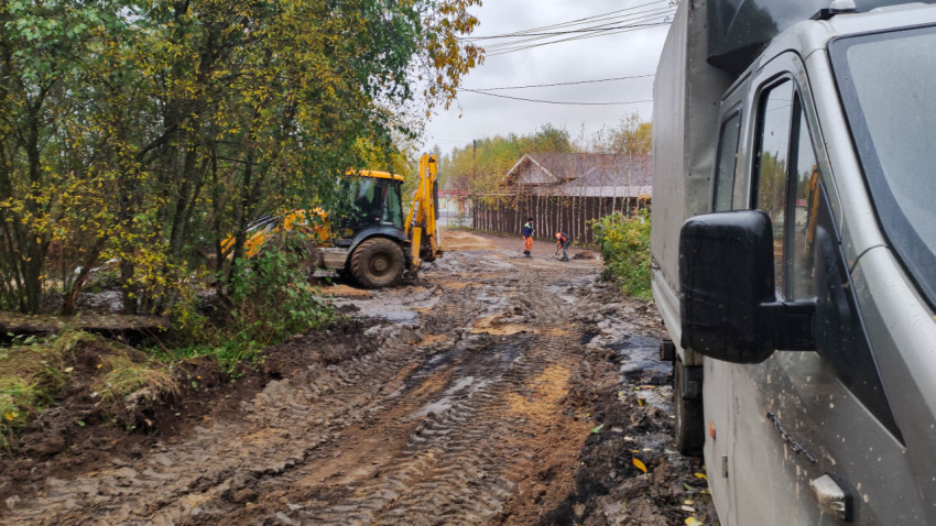 Экскаватор и рабочие на грязной дороге в деревне