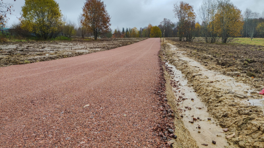 Гравийная дорога с укреплёнными краями и водоотводной канавой в сельской местности