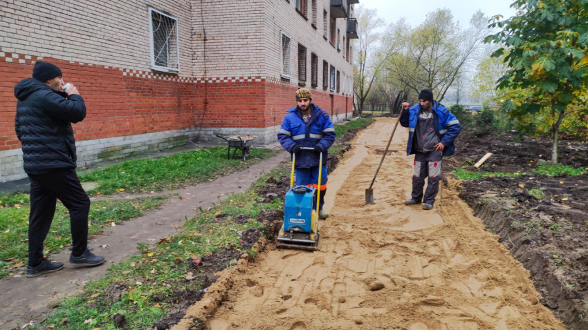 Строительные работы по подготовке основания для пешеходной дорожки возле жилого дома