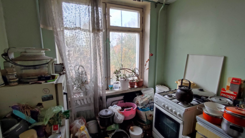 Захламленная кухня с газовой плитой и окном