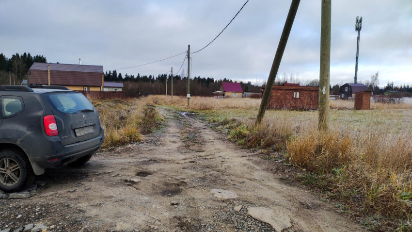 Грунтовая дорога в сельской местности с электростолбами и жилыми домами